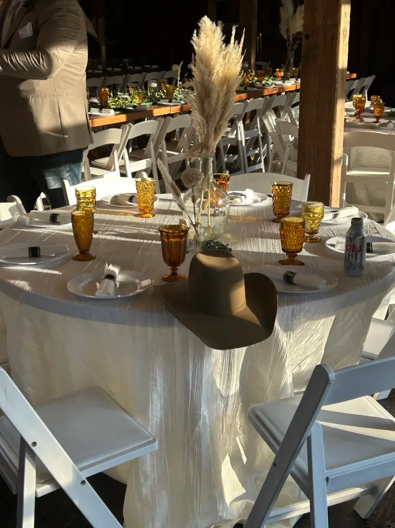 Reception table laid with amber glassware and a felt hat at one setting