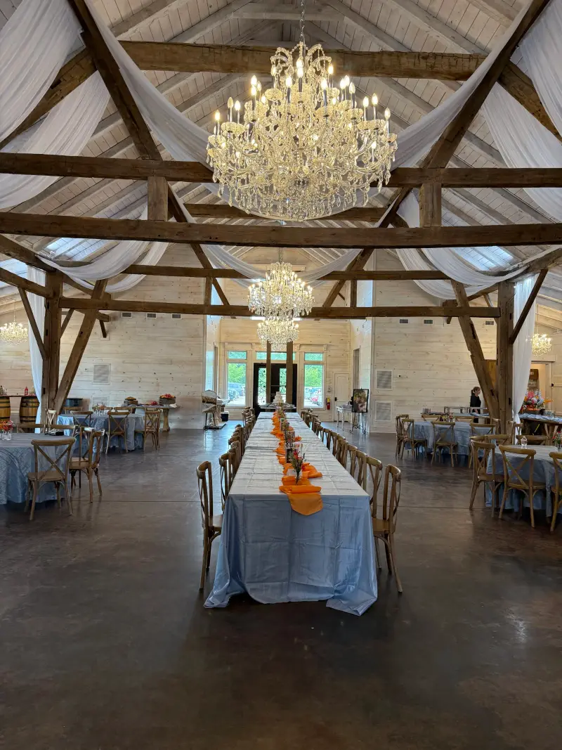 Barn reception hall with a chandelier above a long head table