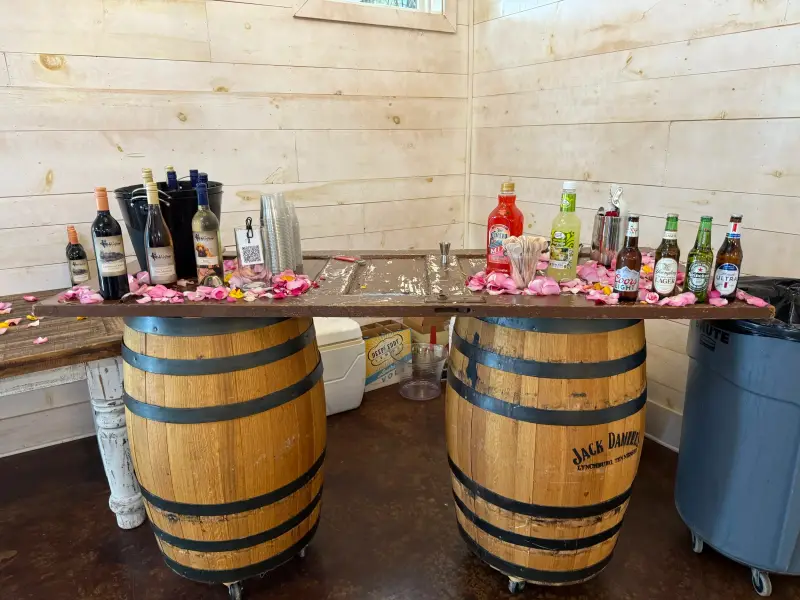Whiskey barrel bar stocked with wine and mixers, rose petals scattered across the top