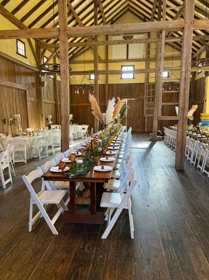 Long farmhouse table set for dinner down the centre of a rustic barn