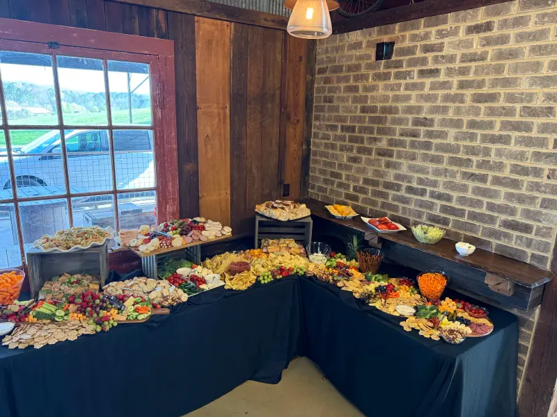 Long buffet of appetizers laid out on navy linens against a brick wall