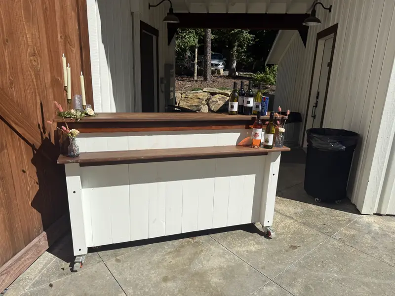 White portable bar with a walnut top set up outside a venue