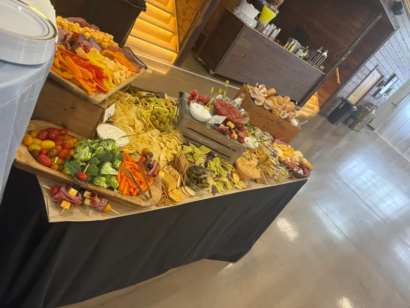 Tiered charcuterie and crudité display on a black-linen buffet