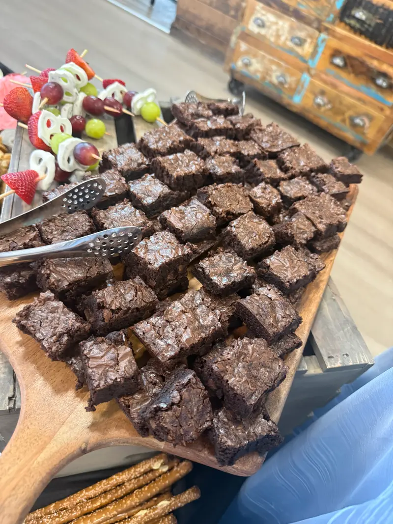 Tray of brownies and fresh fruit skewers on a wooden board