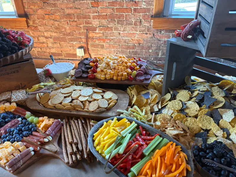 Grazing spread of crackers, cheese cubes, crudité and pretzel sticks on wooden boards