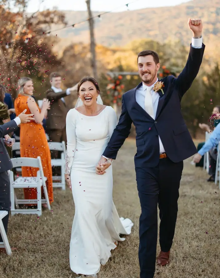Newlyweds walking back up the aisle hand in hand as guests cheer